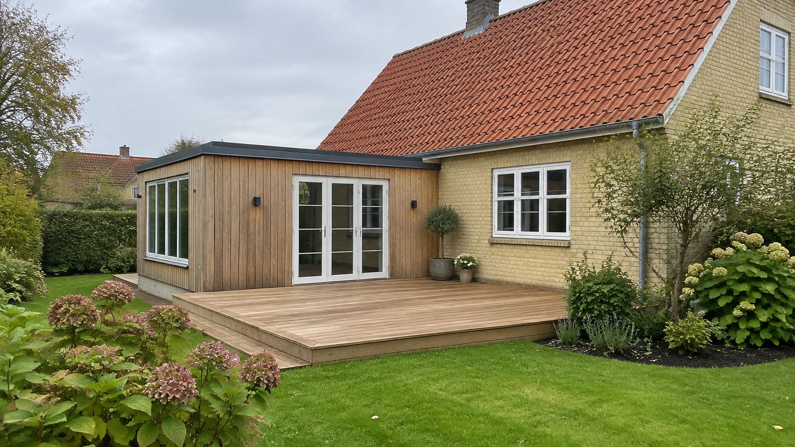 Ny træterrasse af friske træbrædder ved dansk villa med rødt tegltag og tilbygning i træbeklædning